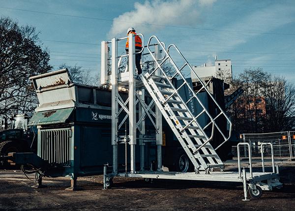 Fahrbare und höhenverstellbare Arbeitsplattform mit Treppenaufgang an einer Sortiermaschine Flexible Steigtechnik-Lösungen für die Industrie